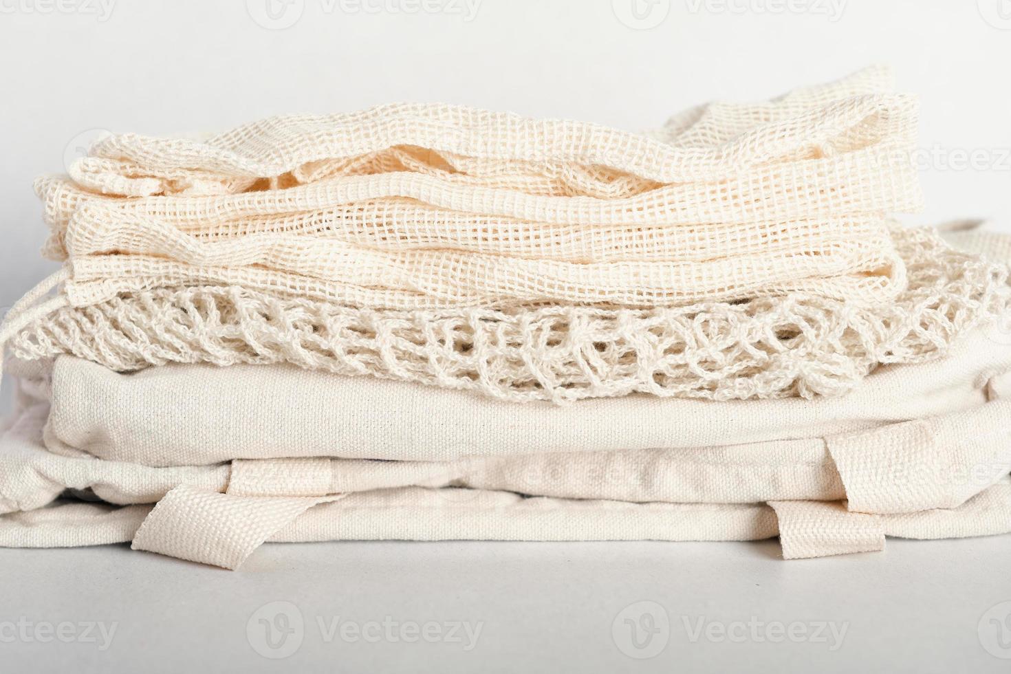 stack of eco friendly bags on a grey background. String and canvas bags made of cotton threads. Zero waste lifestyle. eco shoppers. reusable sustainalbe shopping. photo