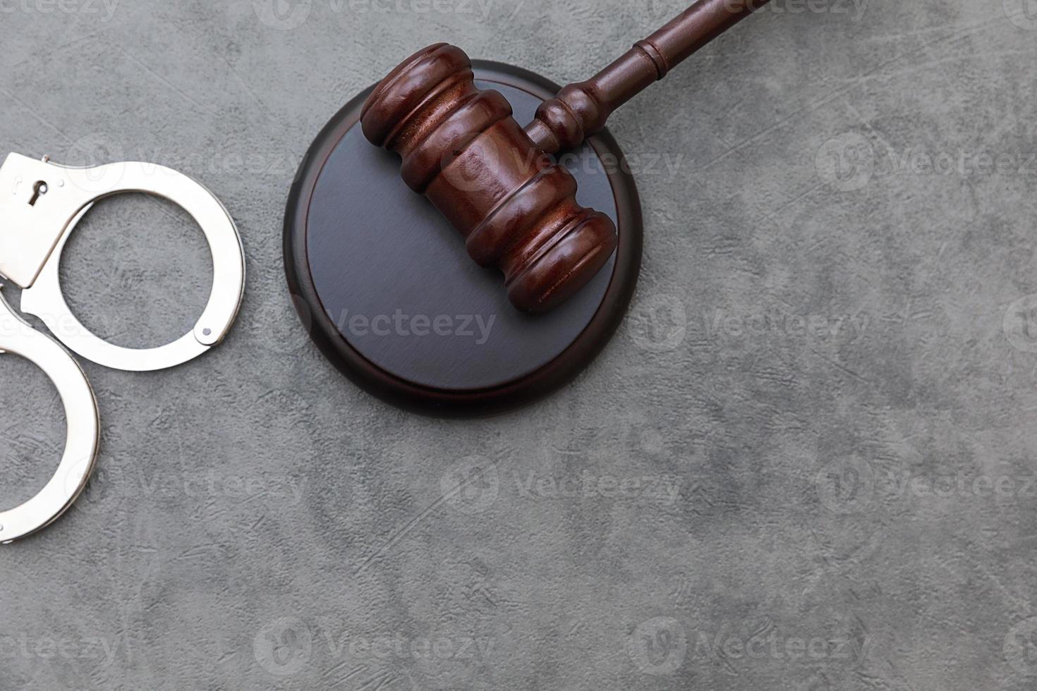 Law theme. Court of law trial in session. Judge gavel handcuffs on grey table in lawyer office or court session. Mallet of judge on concrete stone grey background. Justice human rights concept. photo