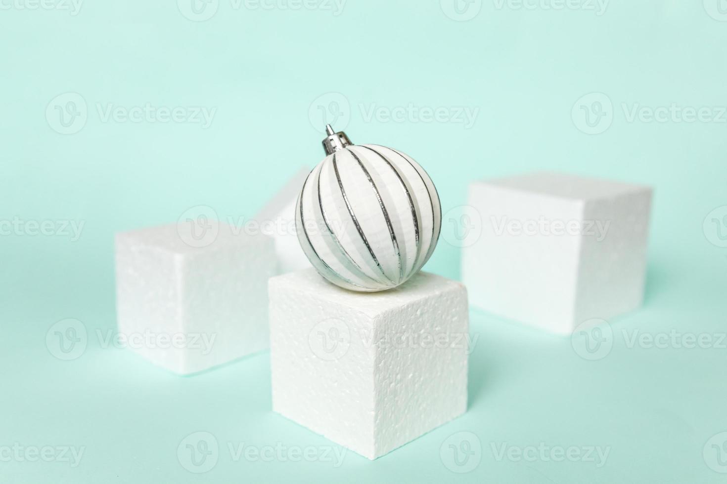 Simply minimal composition winter objects ornament and cube shapes geometric form podium isolated blue pastel background. Christmas New Year december time for celebration concept. Mockup, copy space photo