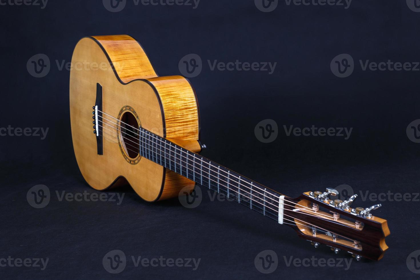 Tuning pegs on wooden machine head of six strings acoustic guitar neck on black background photo