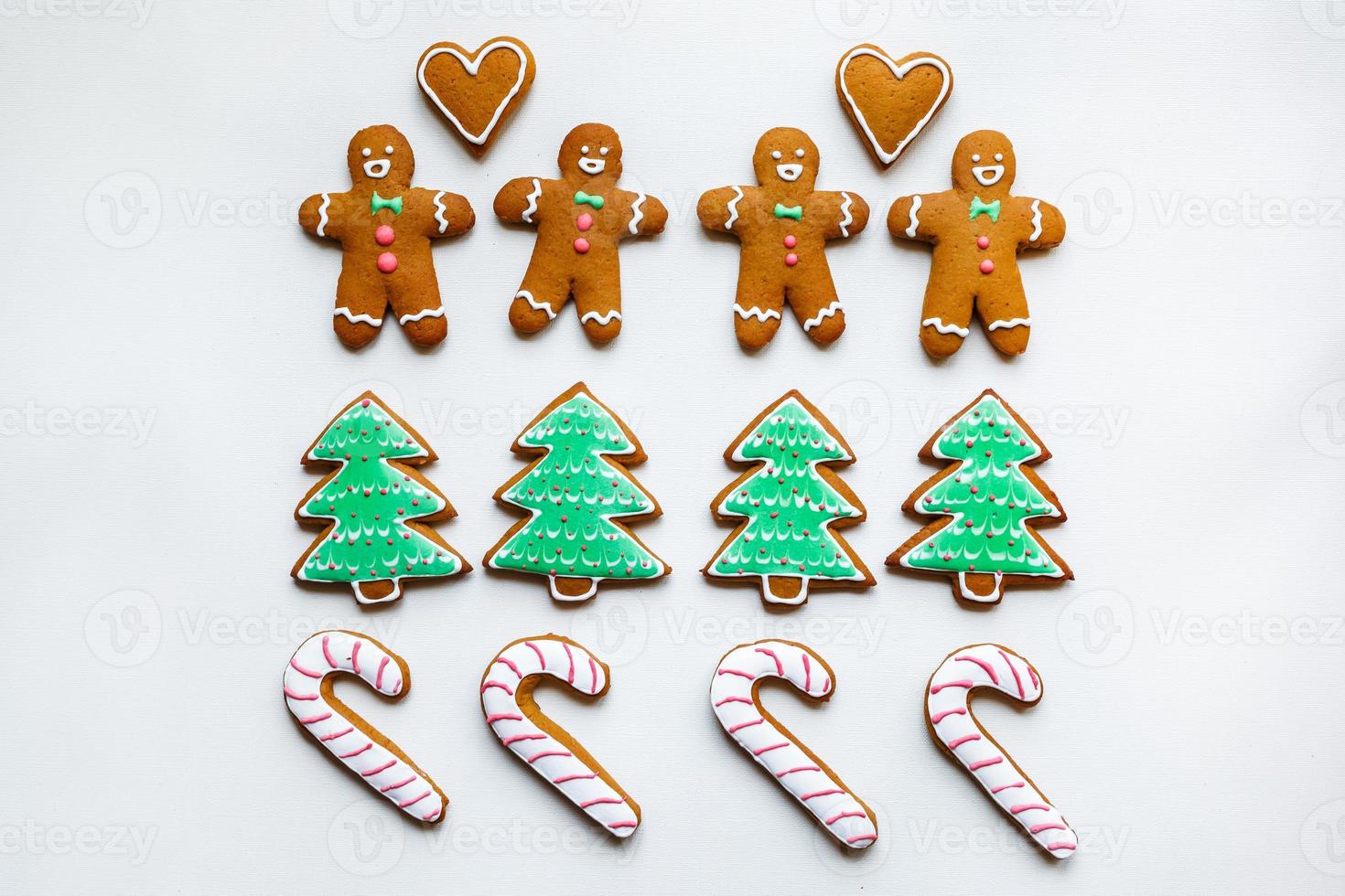 Handmade festive gingerbread cookies in the form of stars, snowflakes, people, socks, staff, mittens, Christmas trees, hearts for xmas and new year holiday on white paper background photo