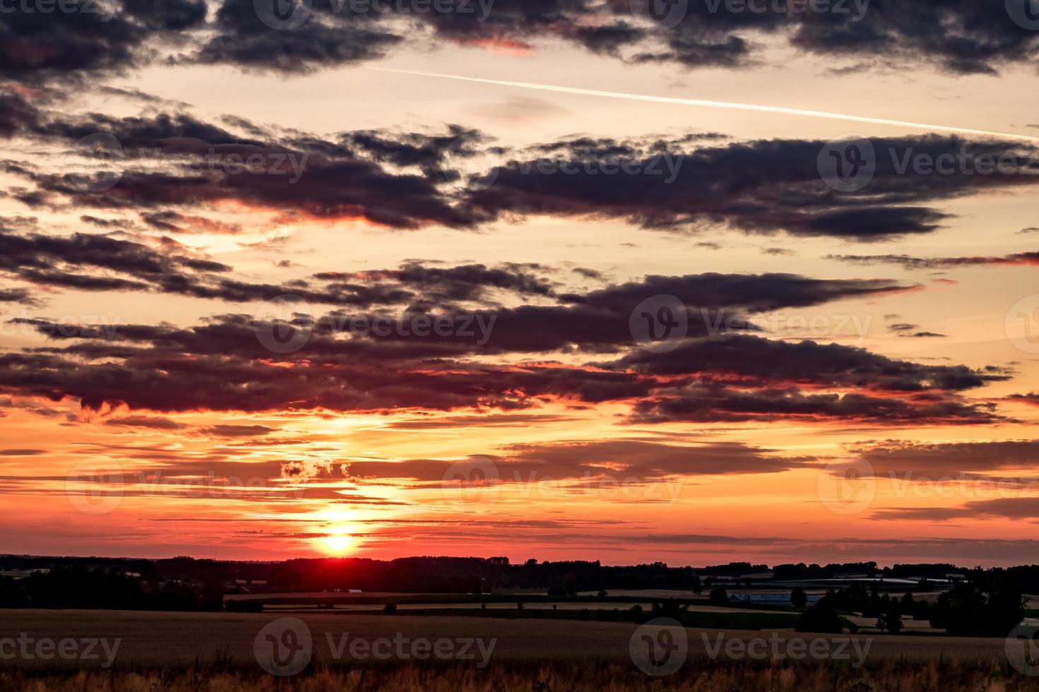 Blue red sky background with evening fluffy curly rolling clouds with setting sun. Good windy weather photo