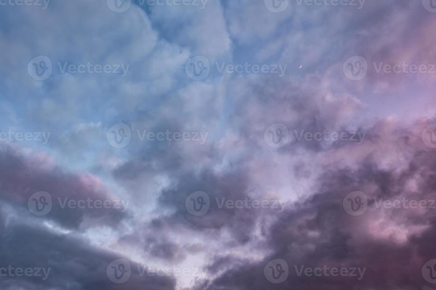 Blue sky background with evening fluffy curly rolling altocumulus altostratus clouds with setting sun. Good windy weather photo