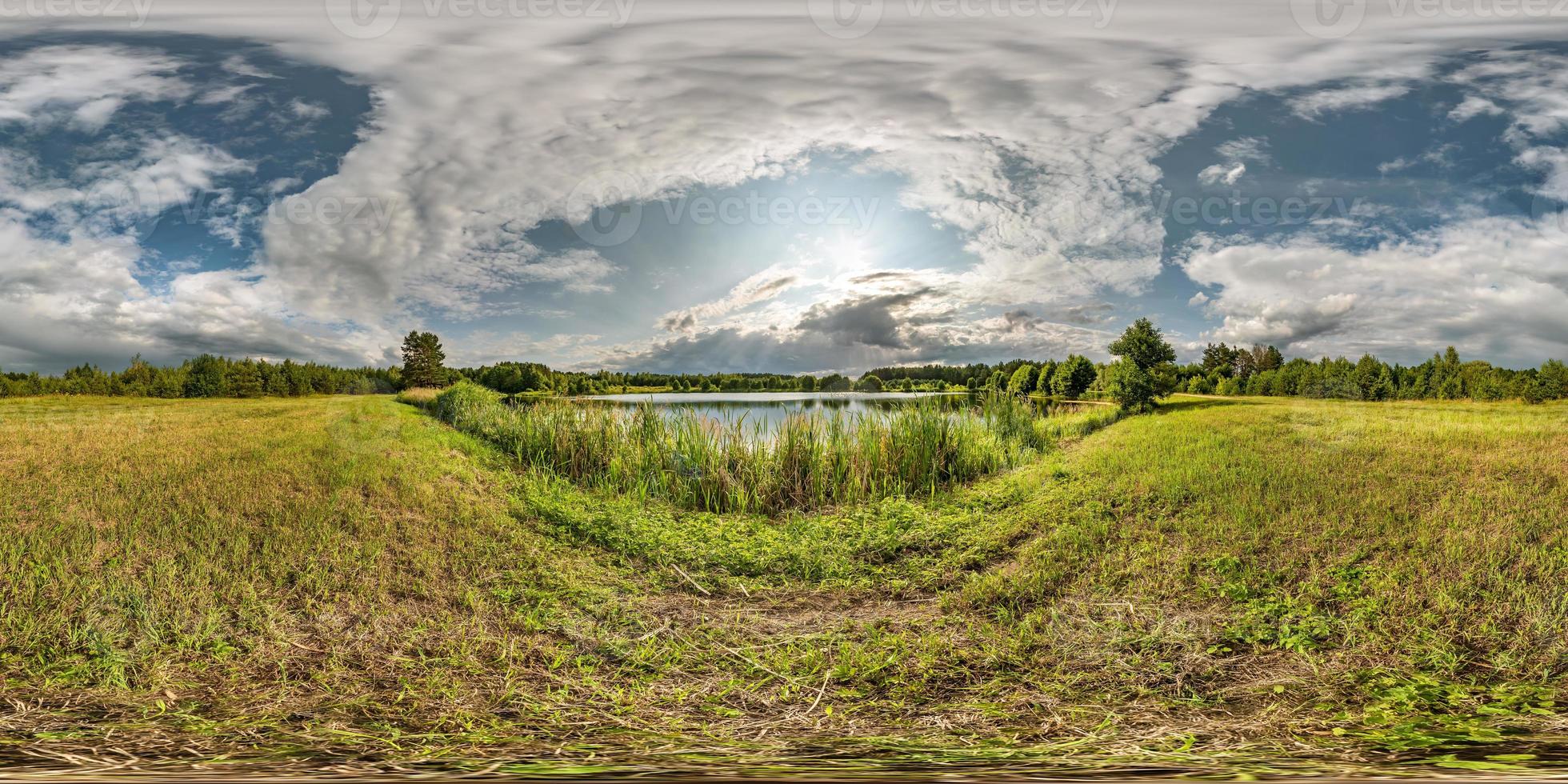 full seamless spherical hdri panorama 360 degrees angle view on grass coast of huge lake or river in sunny summer day and windy weather with beautiful clouds in equirectangular projection, VR content photo