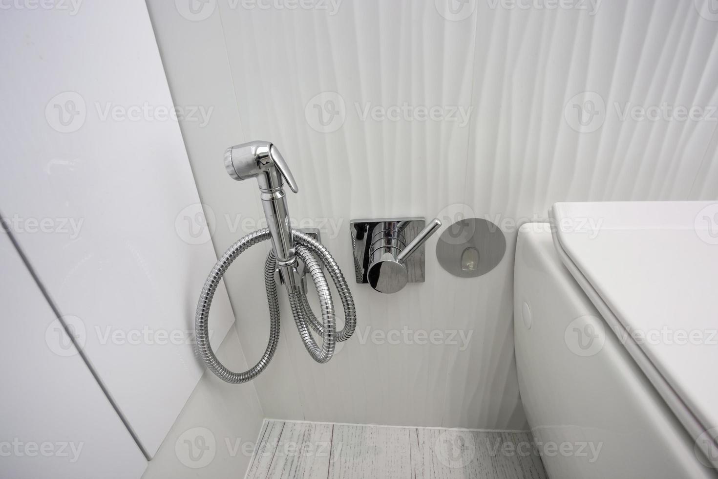toilet and detail of a corner shower bidet with wall mount shower attachment photo