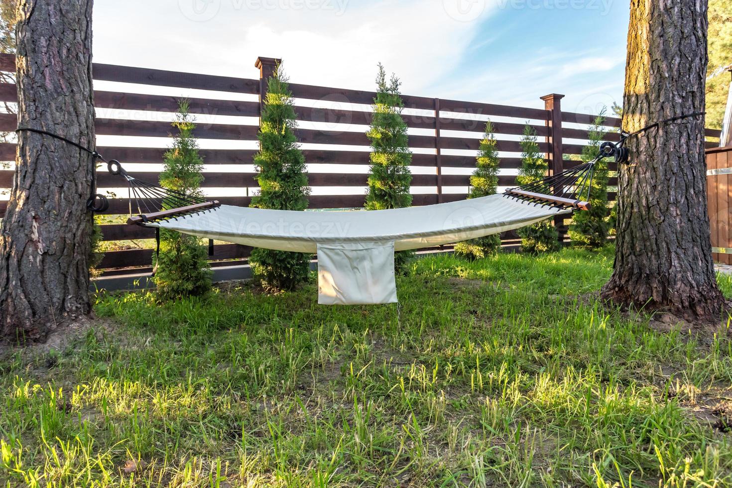 hammock suspended between two pines in summer garden of country house at sunset photo