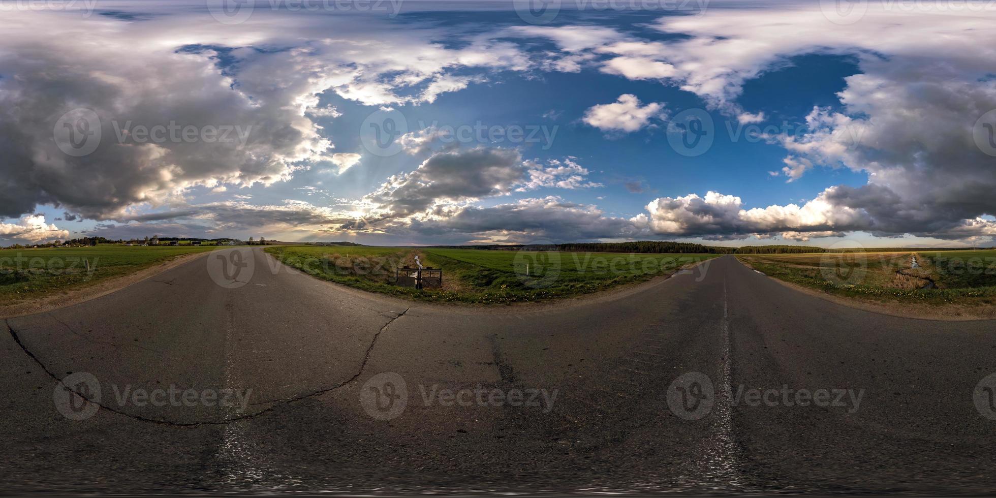 Full spherical seamless hdri panorama 360 degrees angle view on no traffic asphalt road among fields in evening before sunset with cloudy sky. 360 panorama in equirectangular projection, VR AR content photo