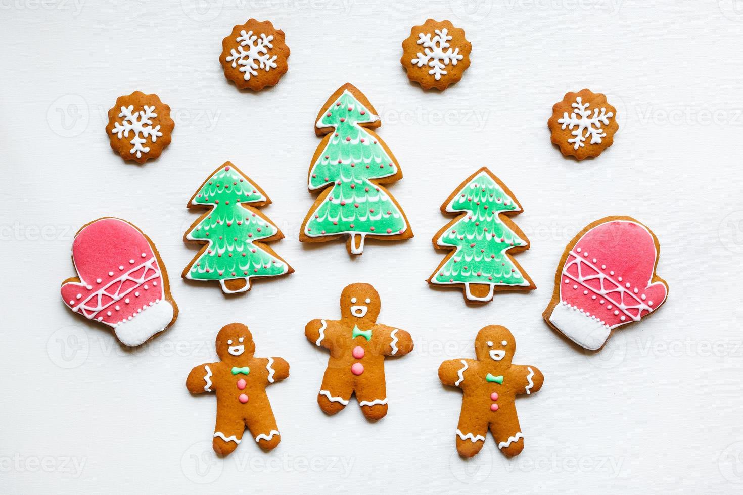 Handmade festive gingerbread cookies in the form of stars, snowflakes, people, socks, staff, mittens, Christmas trees, hearts for xmas and new year holiday on white paper background photo