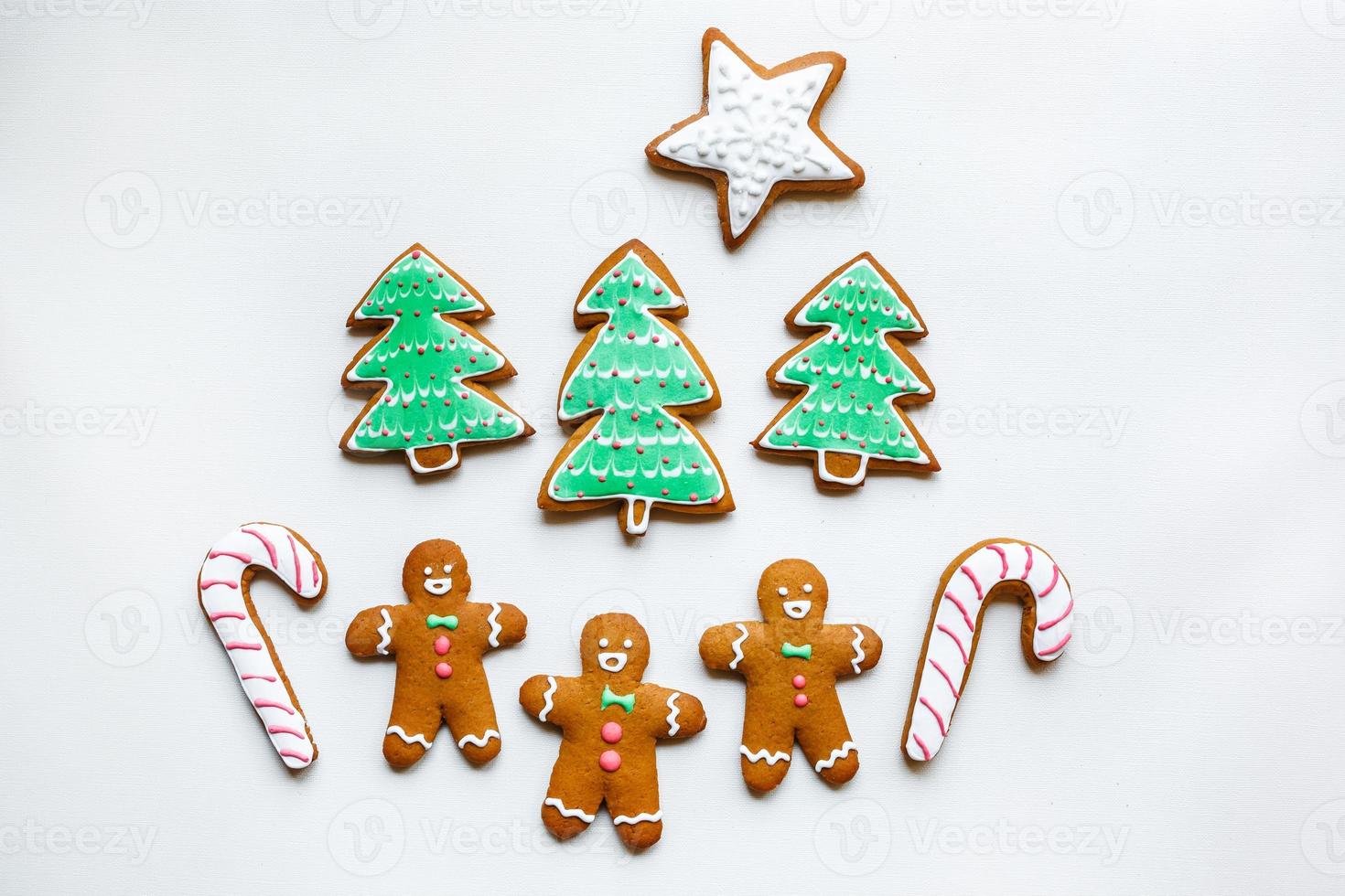 Handmade festive gingerbread cookies in the form of stars, snowflakes, people, socks, staff, mittens, Christmas trees, hearts for xmas and new year holiday on white paper background photo