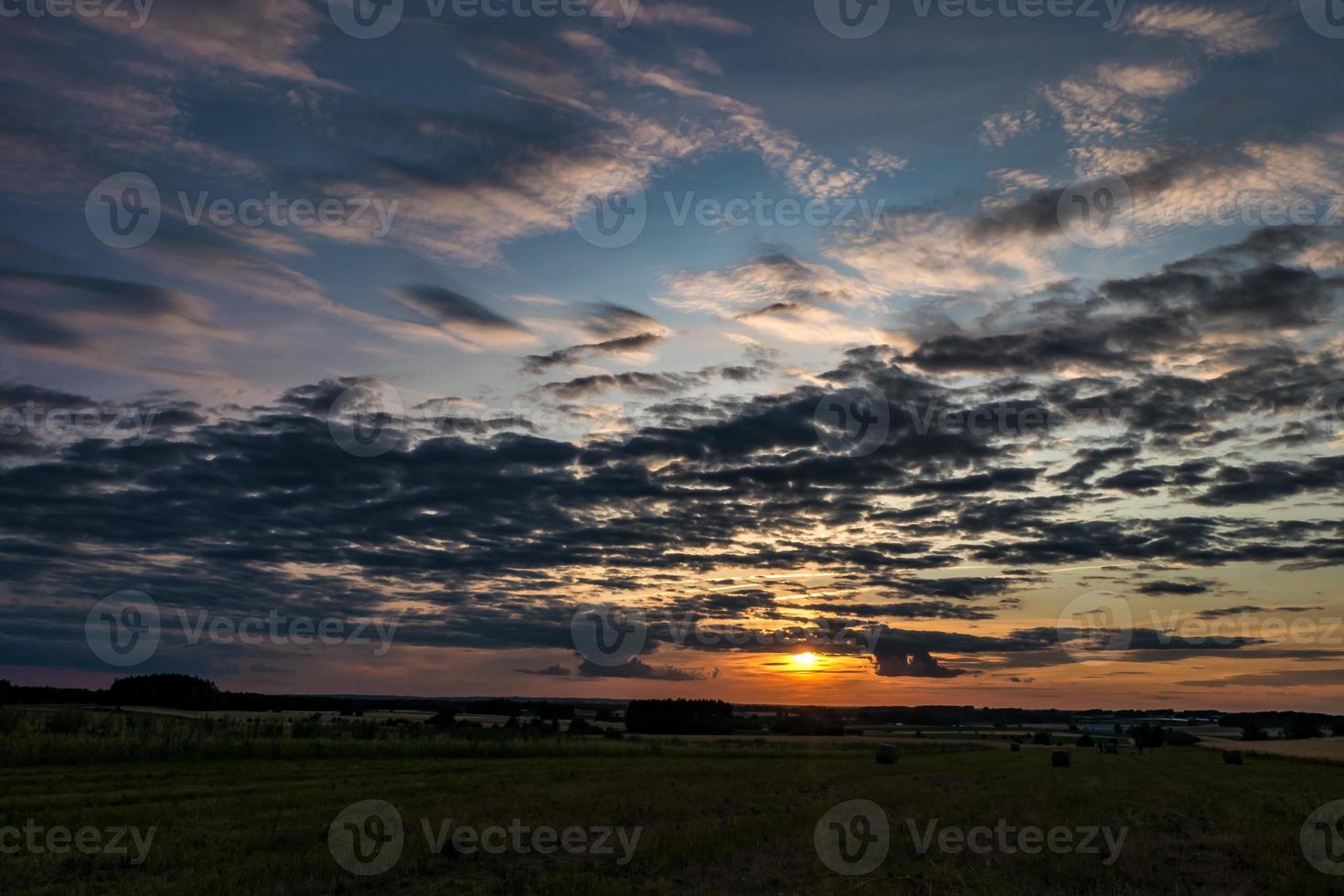 Blue sky background with evening fluffy curly rolling altocumulus altostratus clouds with setting sun. Good windy weather photo
