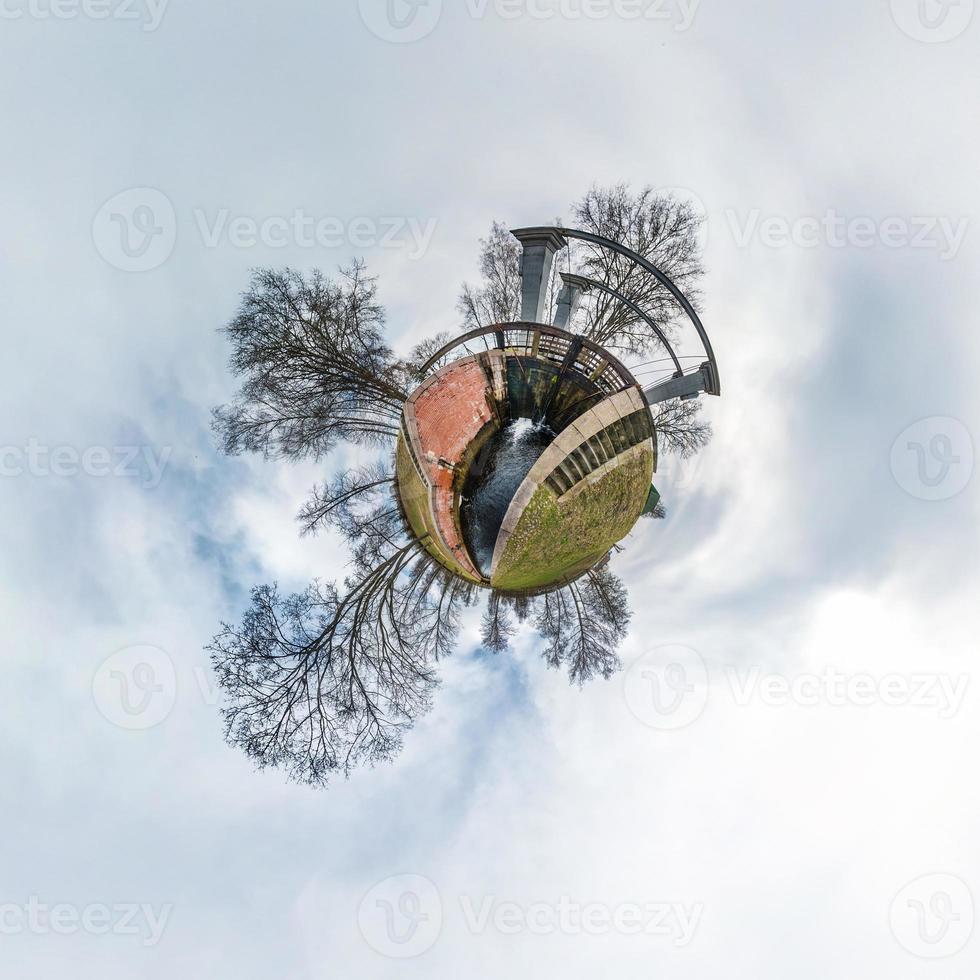 Green little tiny planet with trees near gateway lock sluice construction on river, white clouds and soft blue sky of amusement park. 360 viewing angel. Planet Earth. photo