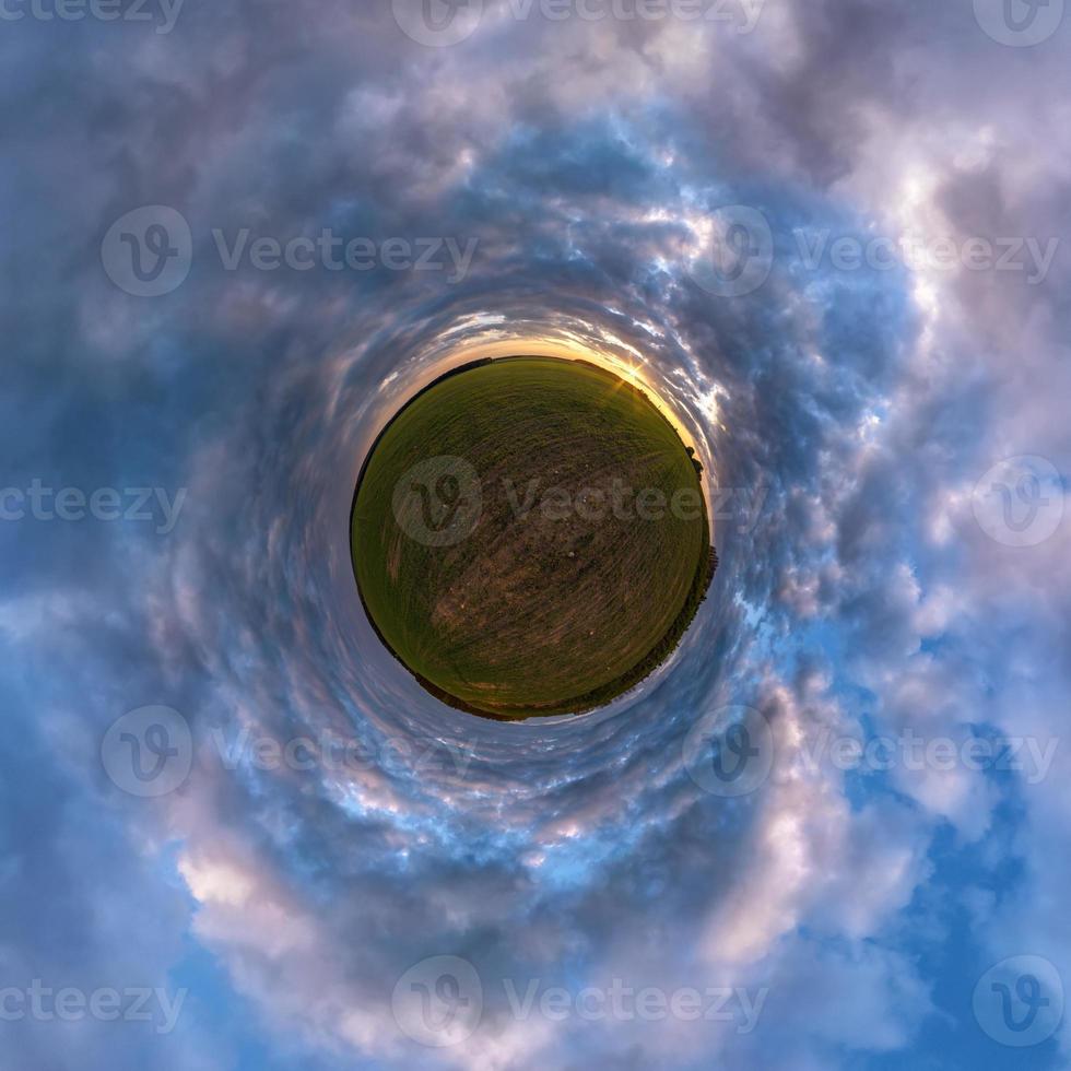 green tiny planet in blue sky with sun and beautiful clouds. Transformation of spherical panorama 360 degrees. Spherical abstract aerial view. Curvature of space. photo