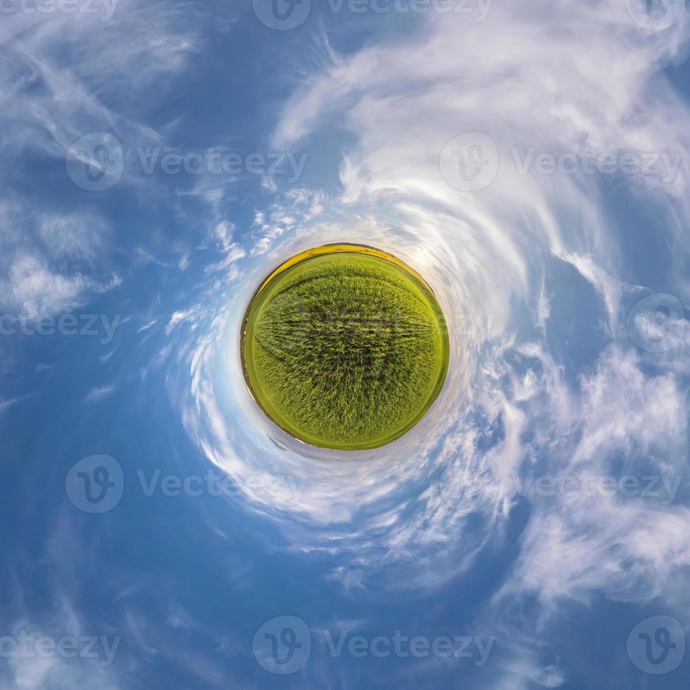 green tiny planet in blue sky with sun and beautiful clouds. Transformation of spherical panorama 360 degrees. Spherical abstract aerial view. Curvature of space. photo