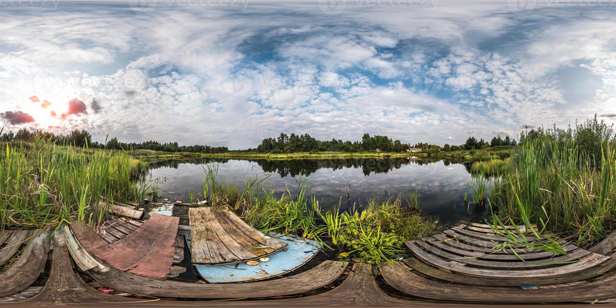 full seamless spherical panorama 360 by 180 angle view on shore with garbage of small lake in sunny summer evening with awesome clouds in equirectangular projection, skybox VR virtual reality content photo