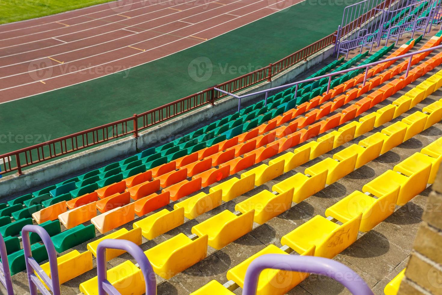 filas multicolores de asientos de plástico en el estadio foto