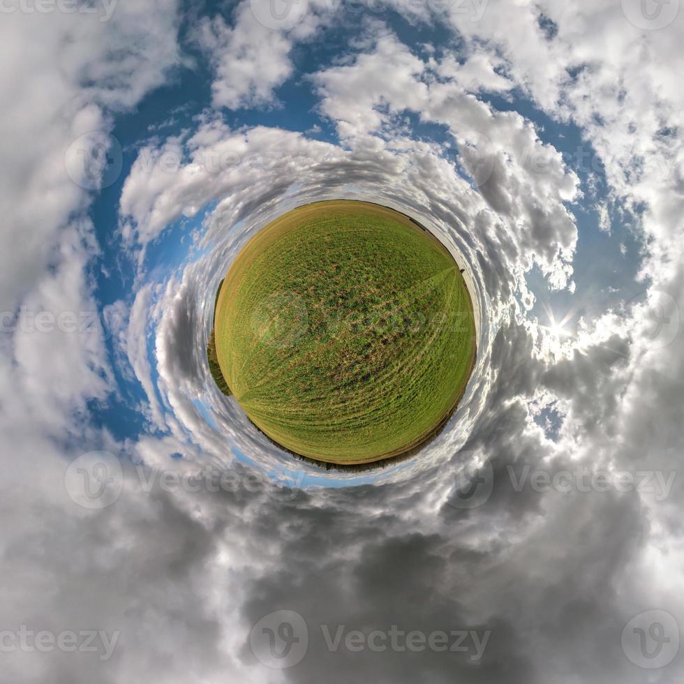 green tiny planet in blue sky with beautiful clouds. Transformation of spherical panorama 360 degrees. Spherical abstract aerial view. Curvature of space. photo