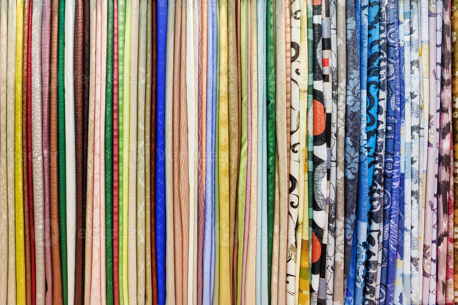 wide selection of different color textile silk fabrics clothes lay in row in drapery store photo