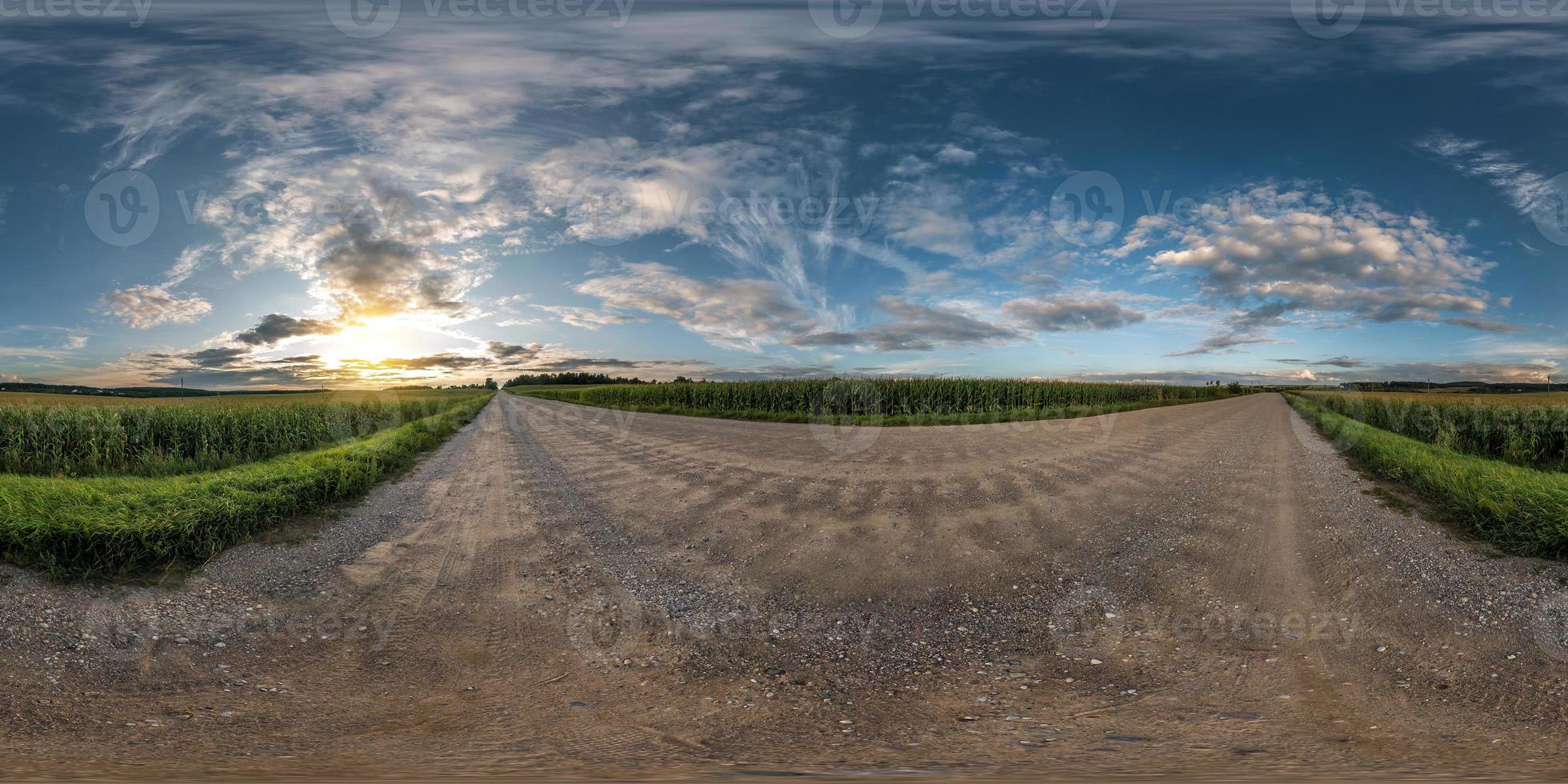 panorama esférico completo sin costuras vista de ángulo de 360 grados en camino de grava entre campos en la puesta de sol de la tarde de verano con nubes impresionantes en proyección equirectangular, skybox vr ar contenido de realidad virtual foto