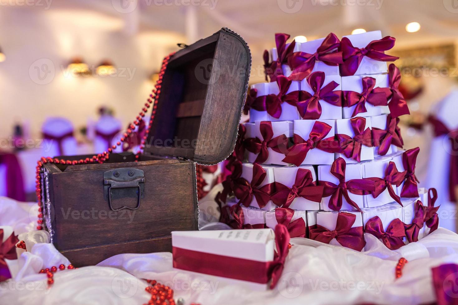 cofre de madera sobre la mesa con un mantel violeta y pequeños regalos para los invitados de los recién casados foto