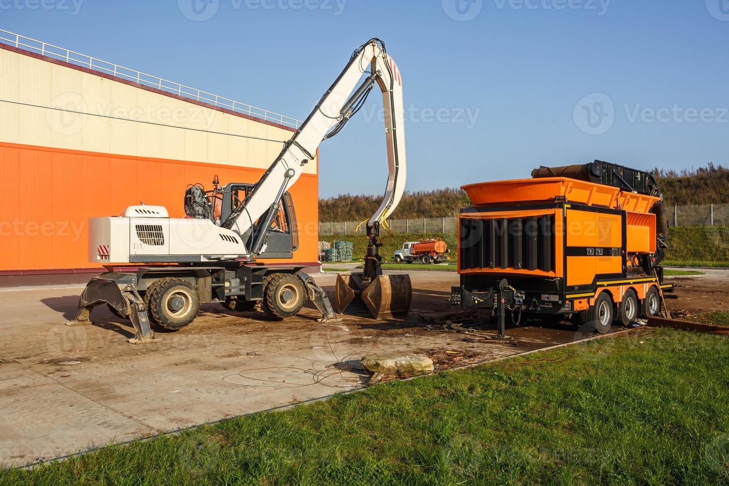 Excavator sorts plastic garbage at waste processing plant. Separate garbage collection. Recycling and storage of waste for further disposal. Business for sorting and processing of waste. photo