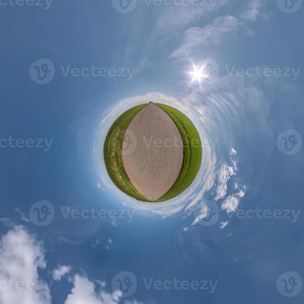 green tiny planet in blue sky with sun and beautiful clouds. Transformation of spherical panorama 360 degrees. Spherical abstract aerial view. Curvature of space. photo