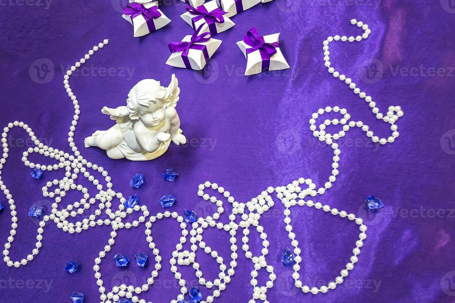ceramic angel on the table with a violet tablecloth and small gifts for guests from the newlyweds photo