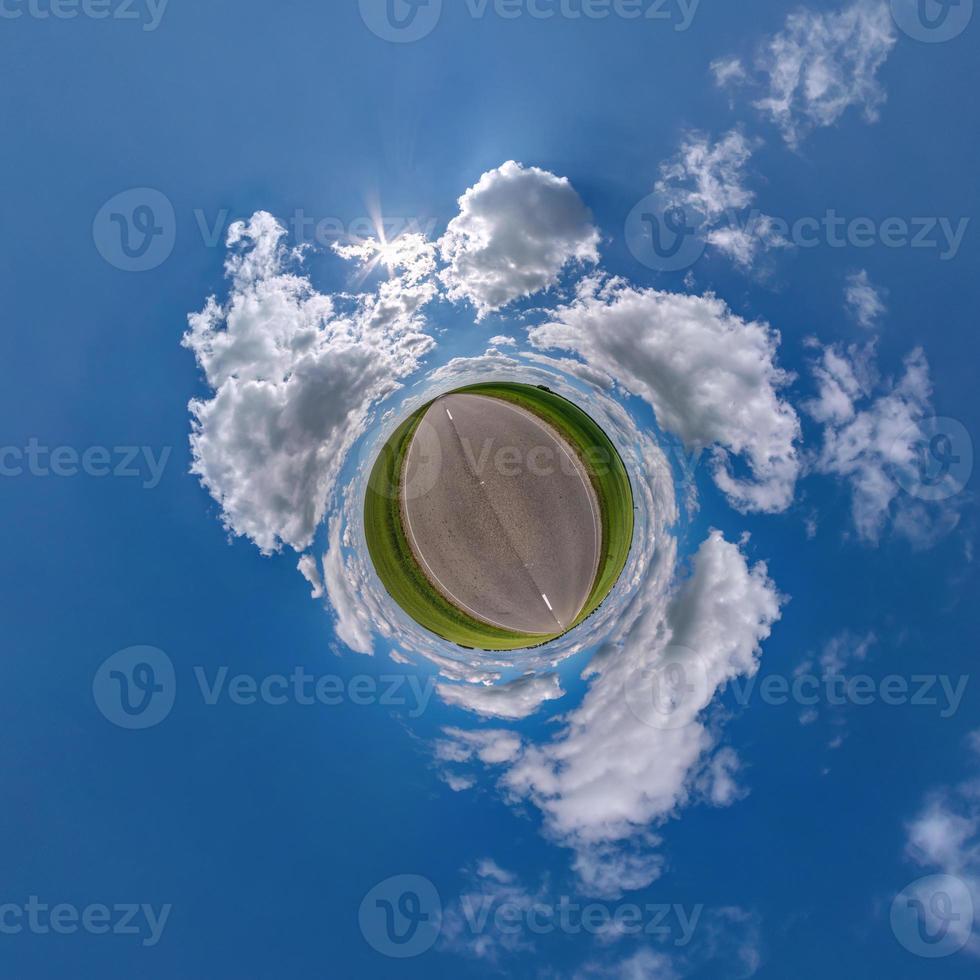 green tiny planet in blue sky with beautiful clouds. Transformation of spherical panorama 360 degrees. Spherical abstract aerial view. Curvature of space. photo