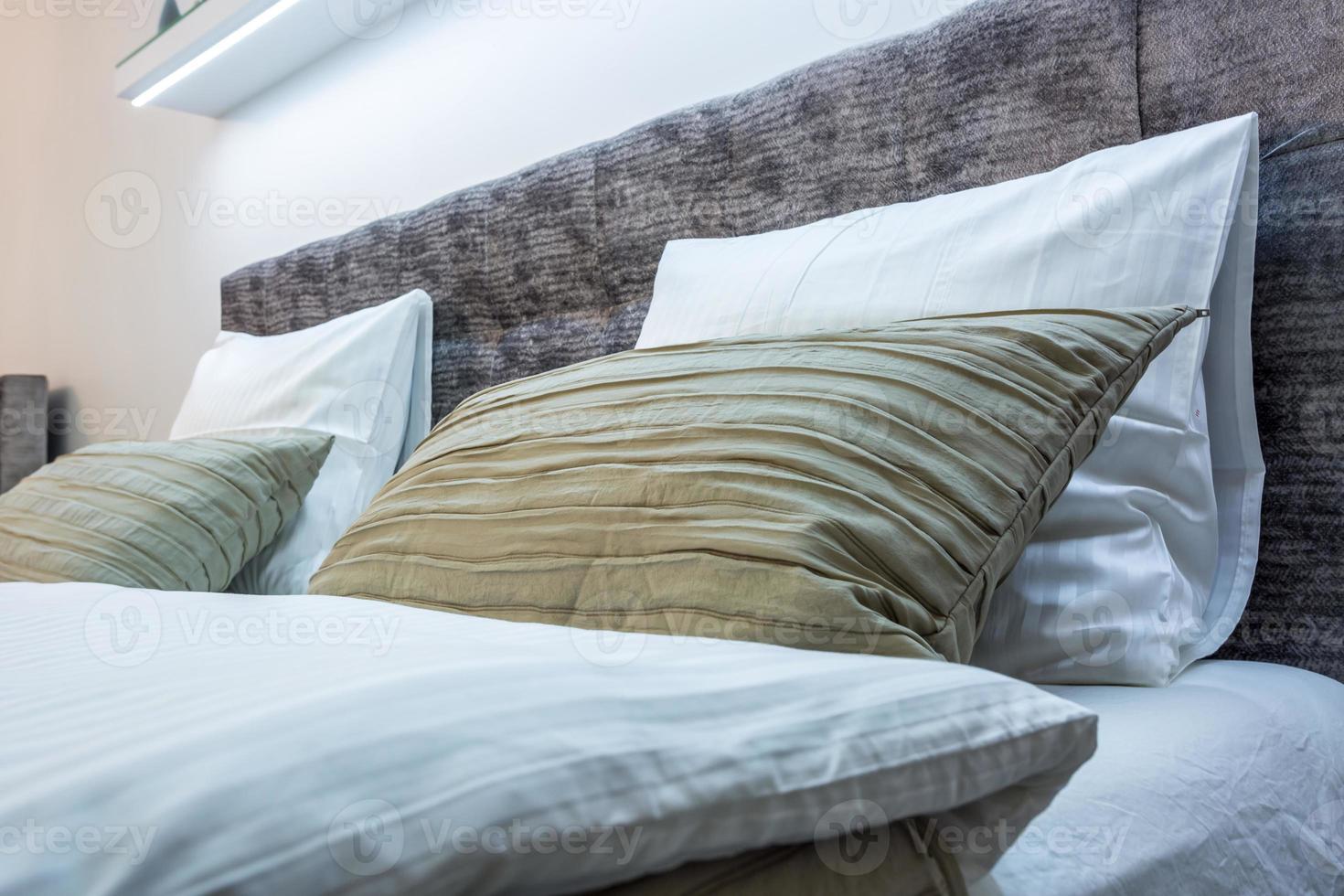 Double bed with pillows in interior of the modern bedroom in loft flat in light color style of expensive apartments photo