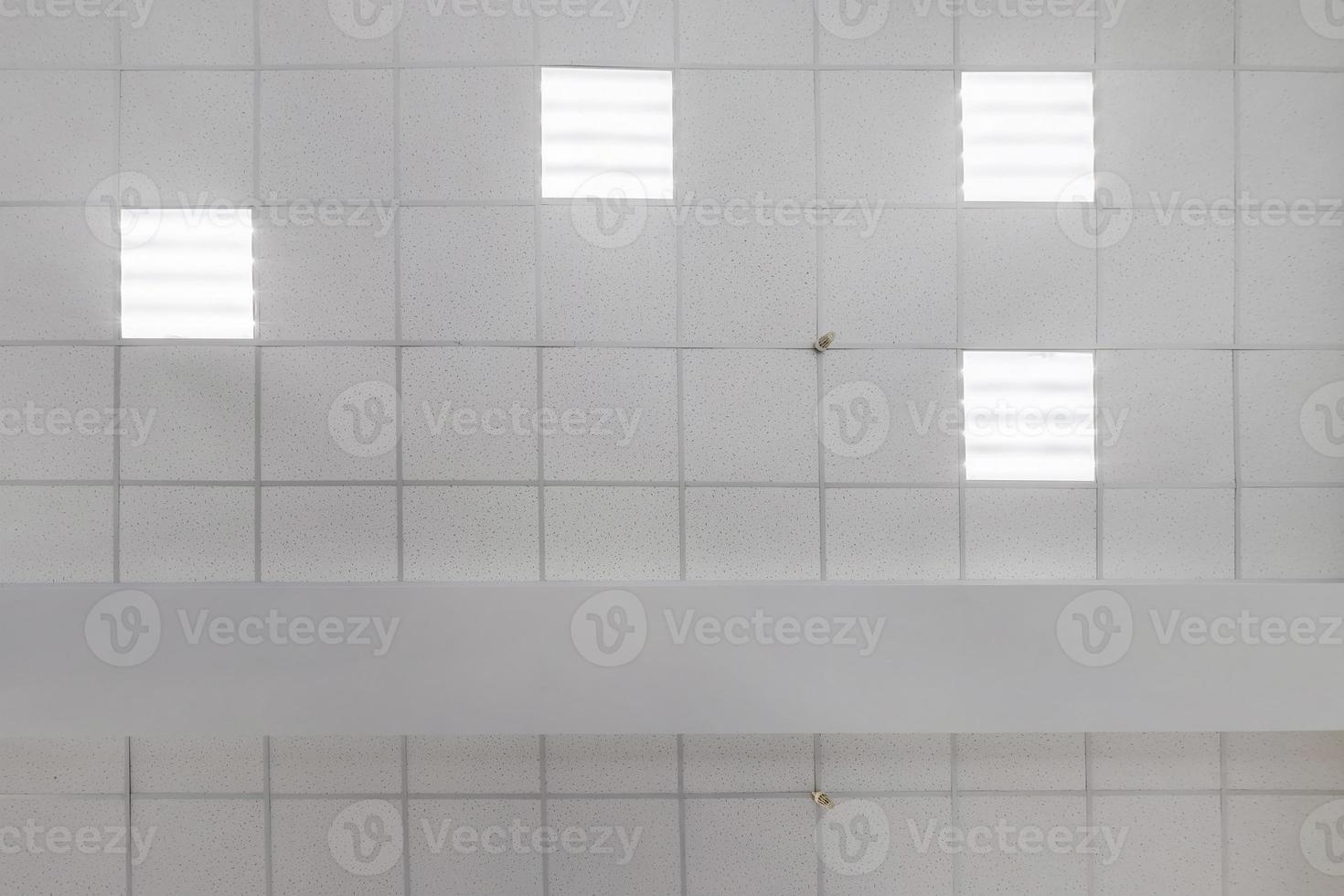 cassette suspended ceiling with square halogen spots lamps and drywall construction in empty room in apartment or house. Stretch ceiling white and complex shape. Looking up view photo