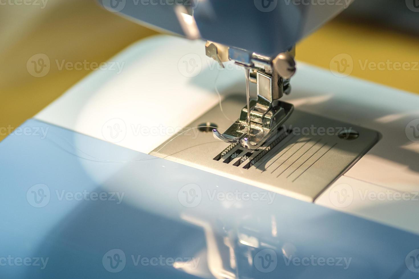 close up mechanism of sewing machine foot  with needle and thread photo