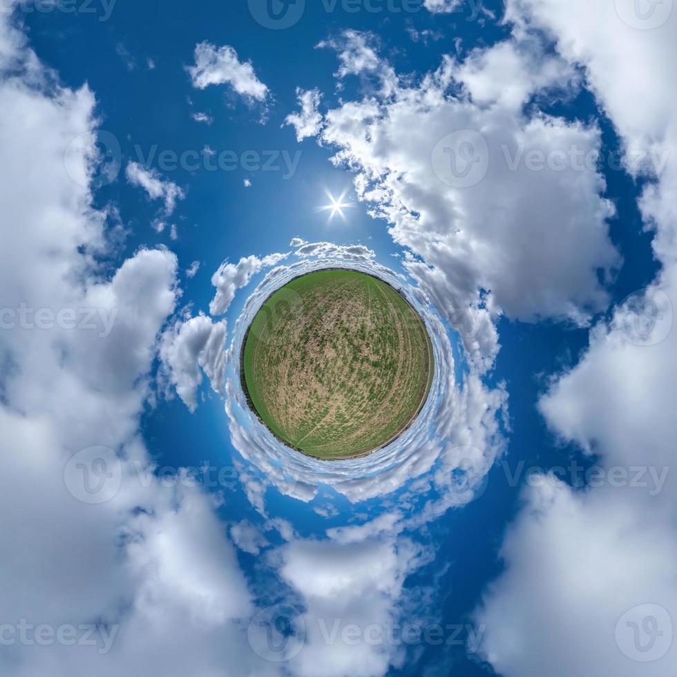 tiny planet in blue sky with beautiful curly clouds. Transformation of spherical panorama 360 degrees. Spherical abstract aerial view. Curvature of space. photo