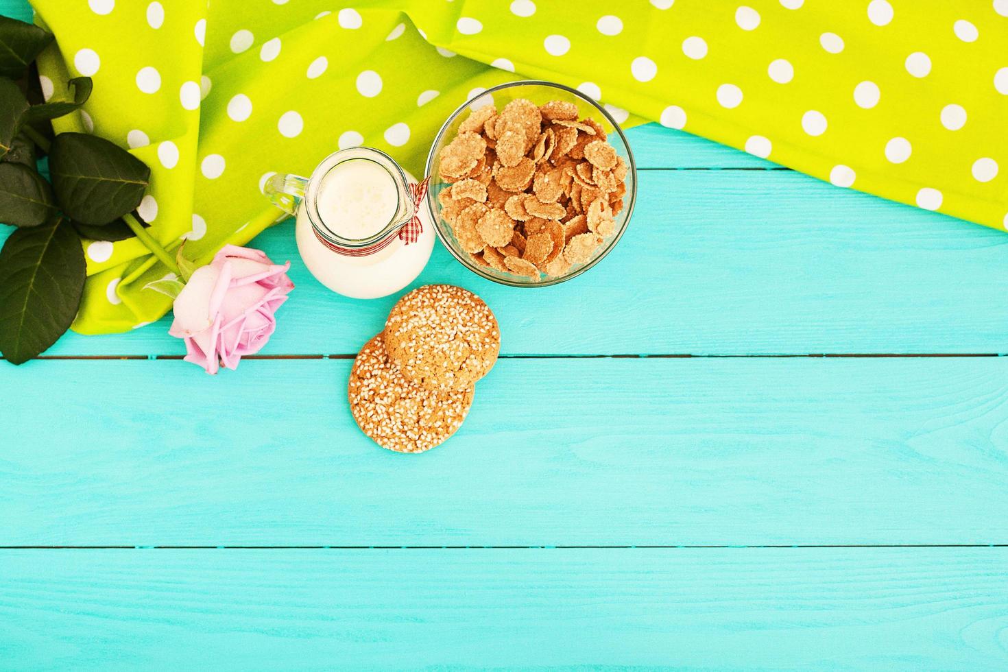 copos de avena y galletas con jarra de leche en la cocina de madera azul. mantel de lunares, rosa rosa. enfoque selectivo foto