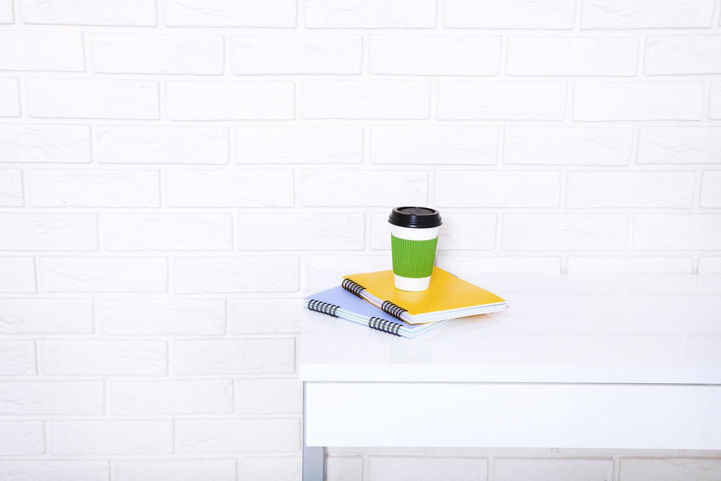 Stylish macro cup of coffee and notebook in office. Selective focus and copy space. Brick wall and workplace business concept. photo