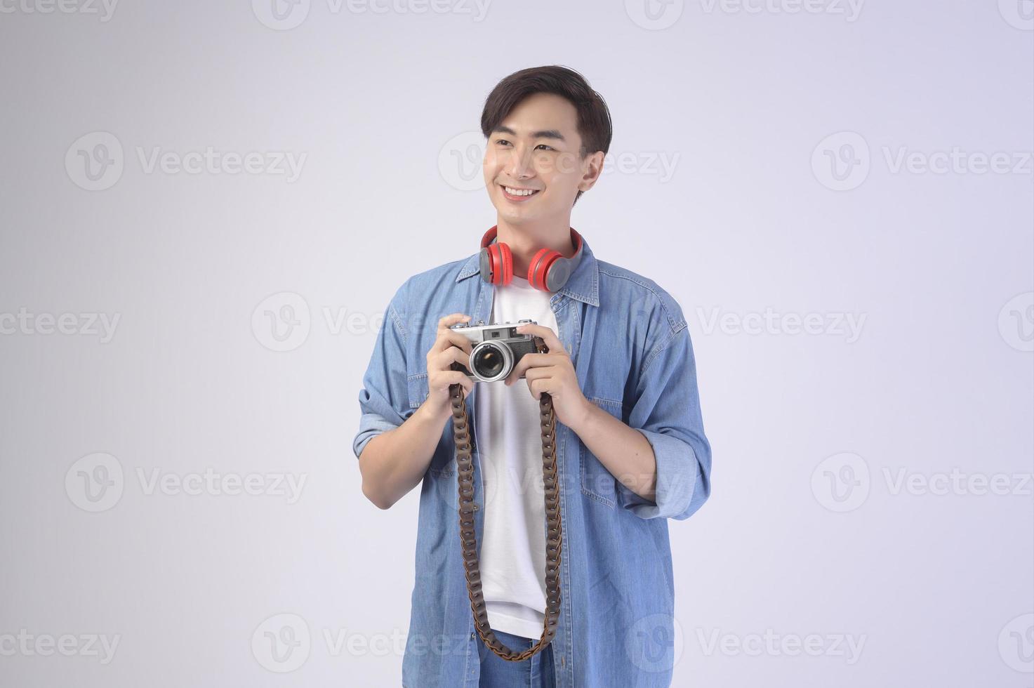 Young happy asian tourist man over white background studio, travel and holidays concept. photo