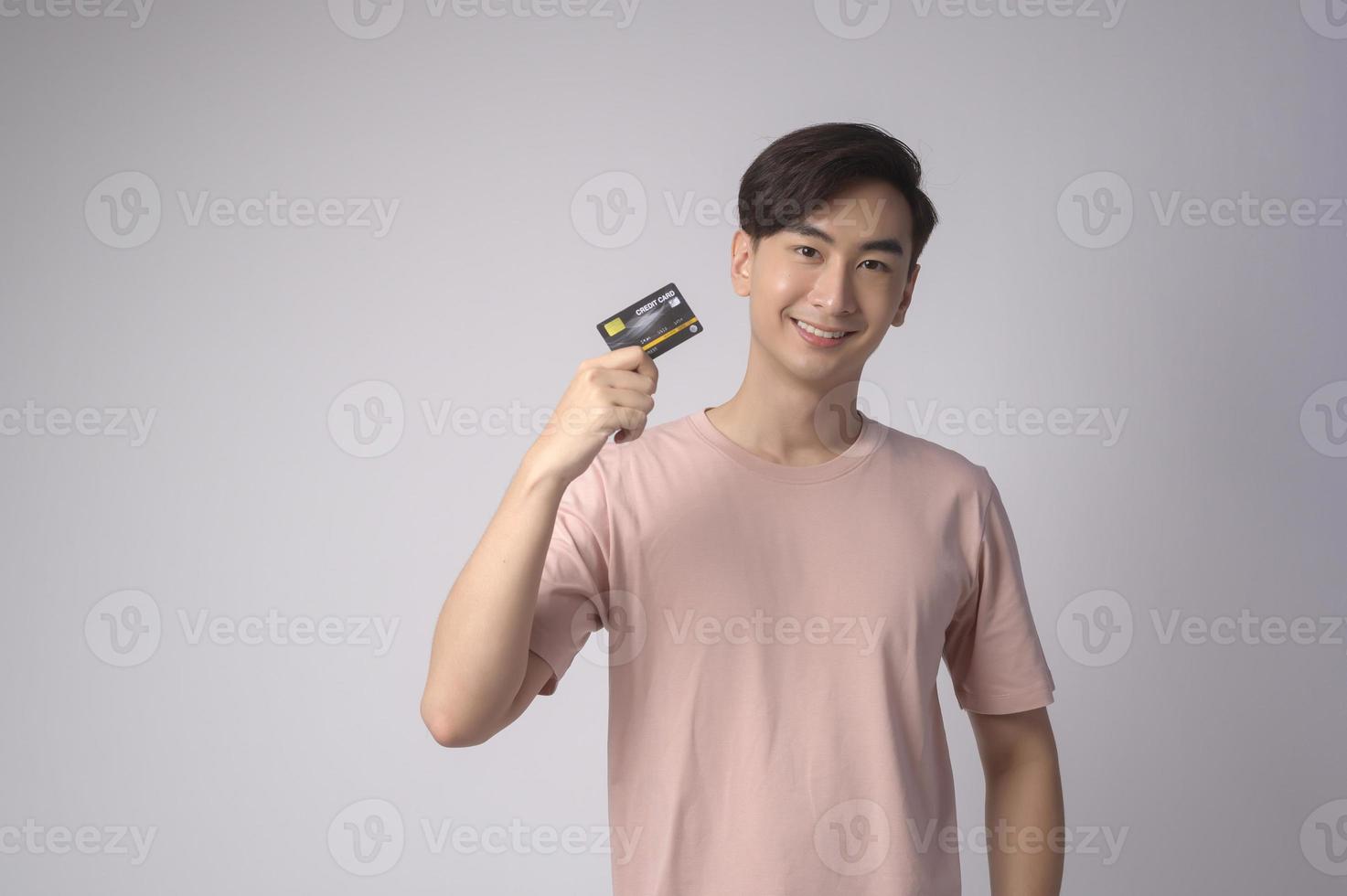 joven asiático con tarjeta de crédito sobre fondo blanco concepto de estudio, compras y finanzas. foto