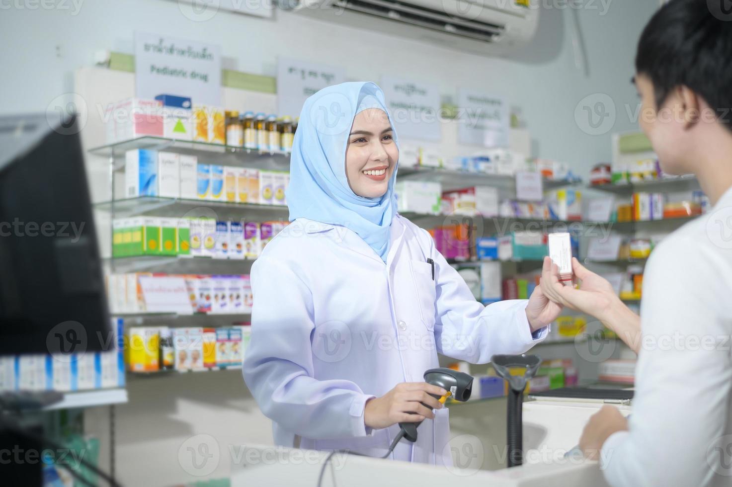 Una farmacéutica musulmana que asesora a una cliente sobre el uso de medicamentos en una farmacia moderna. foto