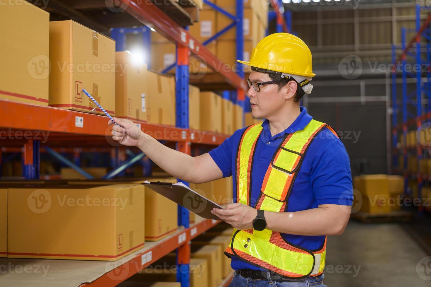 joven trabajador con casco revisando el inventario y contando el producto en el estante en el almacén moderno. foto