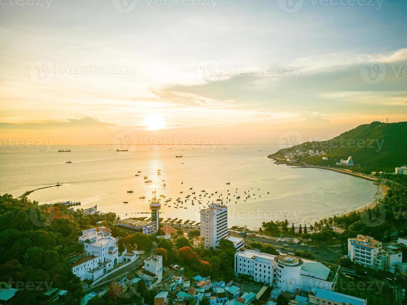 Vung Tau city aerial view with beautiful sunset and so many boats. Panoramic coastal Vung Tau view from above, with waves, coastline, streets, coconut trees and Tao Phung mountain in Vietnam. photo