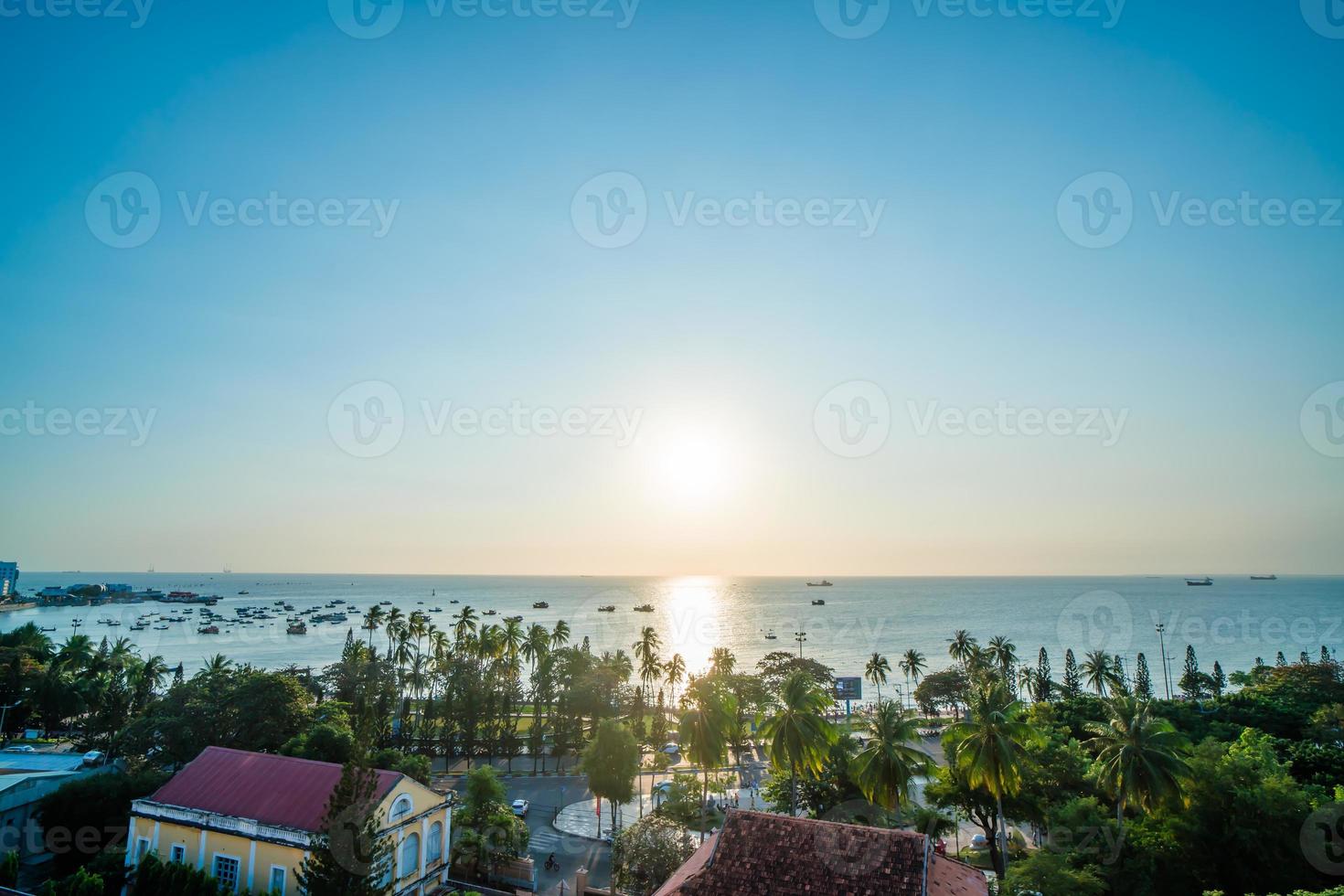 Vung Tau city aerial view with beautiful sunset and so many boats. Panoramic coastal Vung Tau view from above, with waves, coastline, streets, coconut trees and Tao Phung mountain in Vietnam. photo
