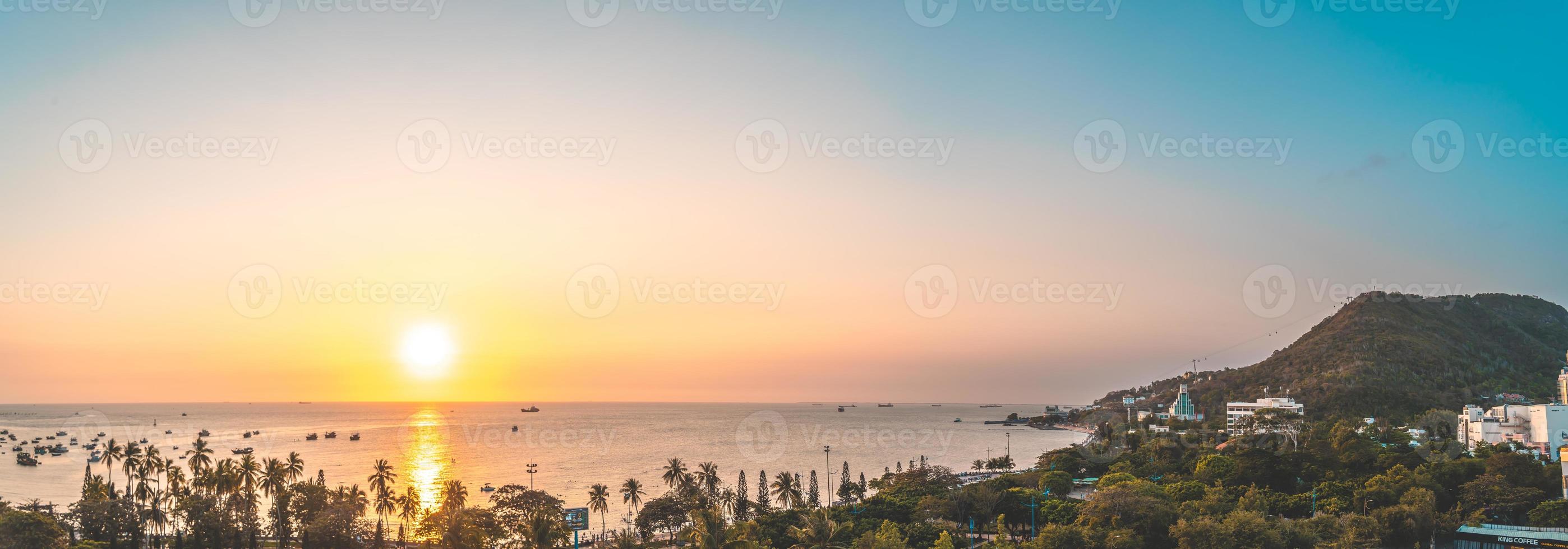 Vung Tau city aerial view with beautiful sunset and so many boats. Panoramic coastal Vung Tau view from above, with waves, coastline, streets, coconut trees and Tao Phung mountain in Vietnam. photo