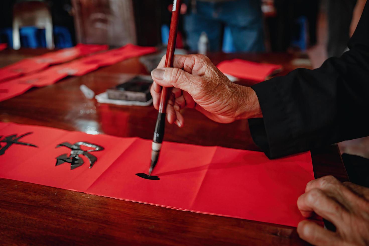 Vietnamese scholar writes calligraphy at Long Son. Calligraphy festival is a popular tradition during Tet holiday. Writing couplets for Spring Festival, new year. photo