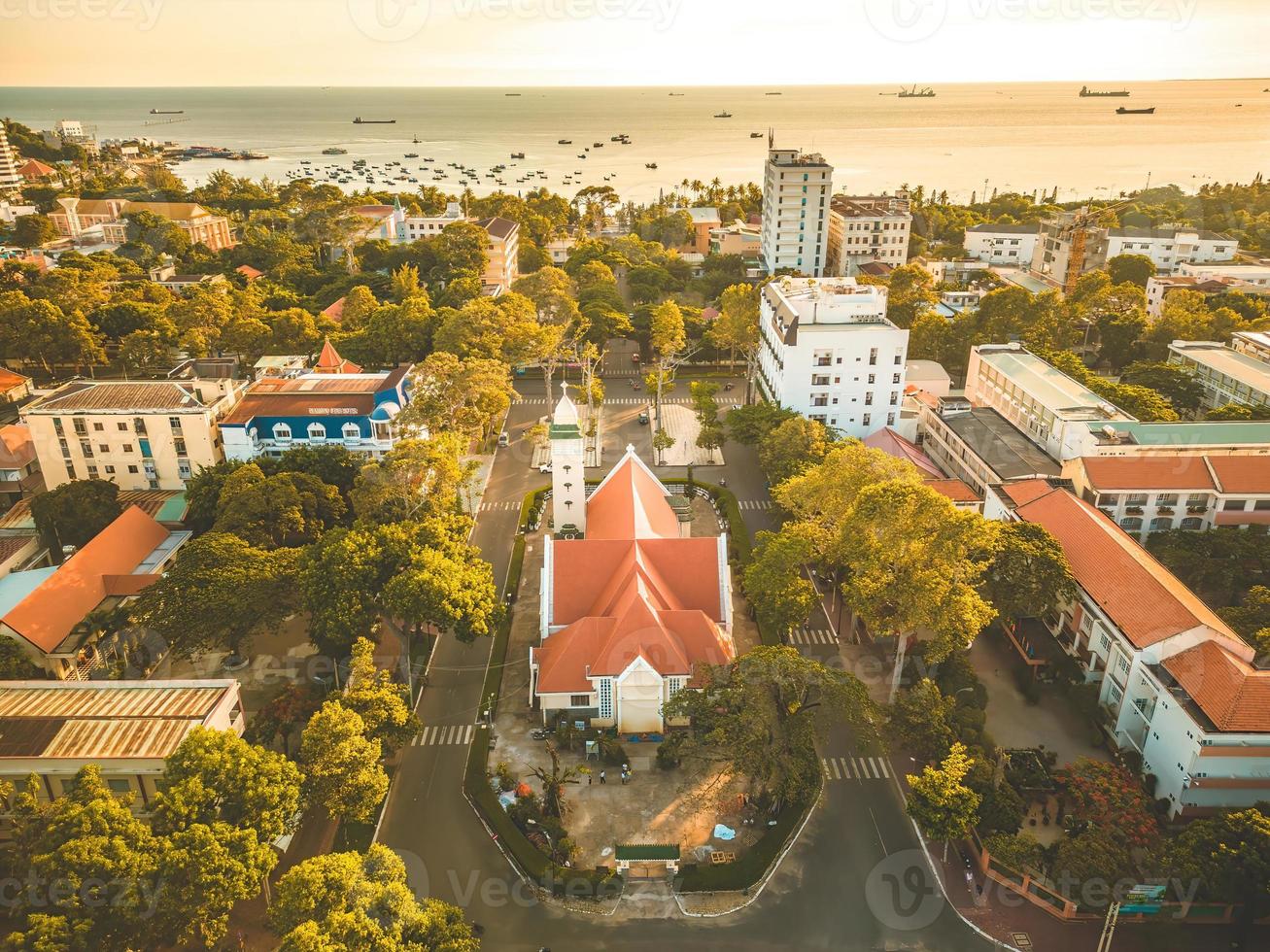 vista superior de la hermosa iglesia antigua de la ciudad de vung tau con árbol verde. pueblo del templo católico de vung tau, vietnam. foto del paisaje primaveral con puesta de sol.