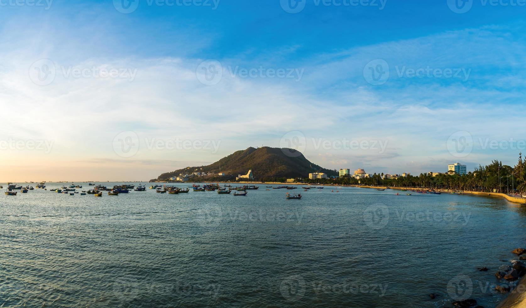 vista aérea de la ciudad de vung tau con hermosa puesta de sol y tantos barcos. vista panorámica costera de vung tau desde arriba, con olas, costa, calles, cocoteros y montaña tao phung en vietnam. foto