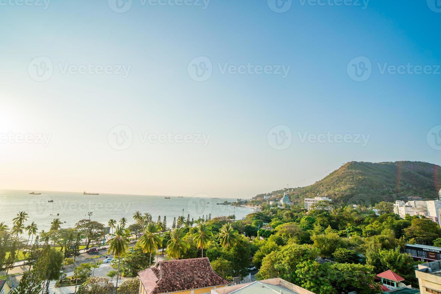 Vung Tau city aerial view with beautiful sunset and so many boats. Panoramic coastal Vung Tau view from above, with waves, coastline, streets, coconut trees and Tao Phung mountain in Vietnam. photo