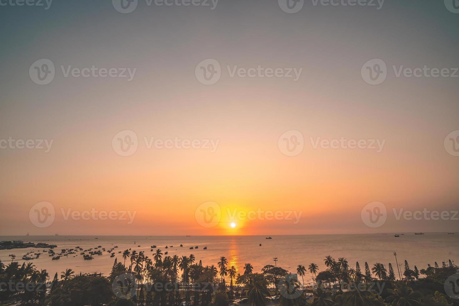 Vung Tau city aerial view with beautiful sunset and so many boats. Panoramic coastal Vung Tau view from above, with waves, coastline, streets, coconut trees and Tao Phung mountain in Vietnam. photo