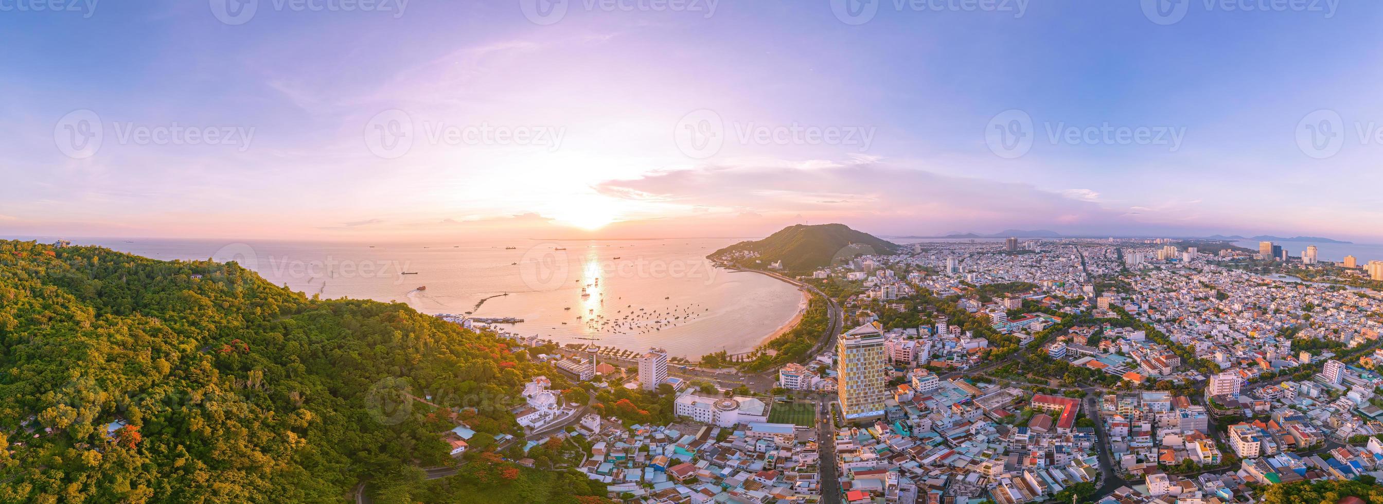 Vung Tau city aerial view with beautiful sunset and so many boats. Panoramic coastal Vung Tau view from above, with waves, coastline, streets, coconut trees and Tao Phung mountain in Vietnam. photo