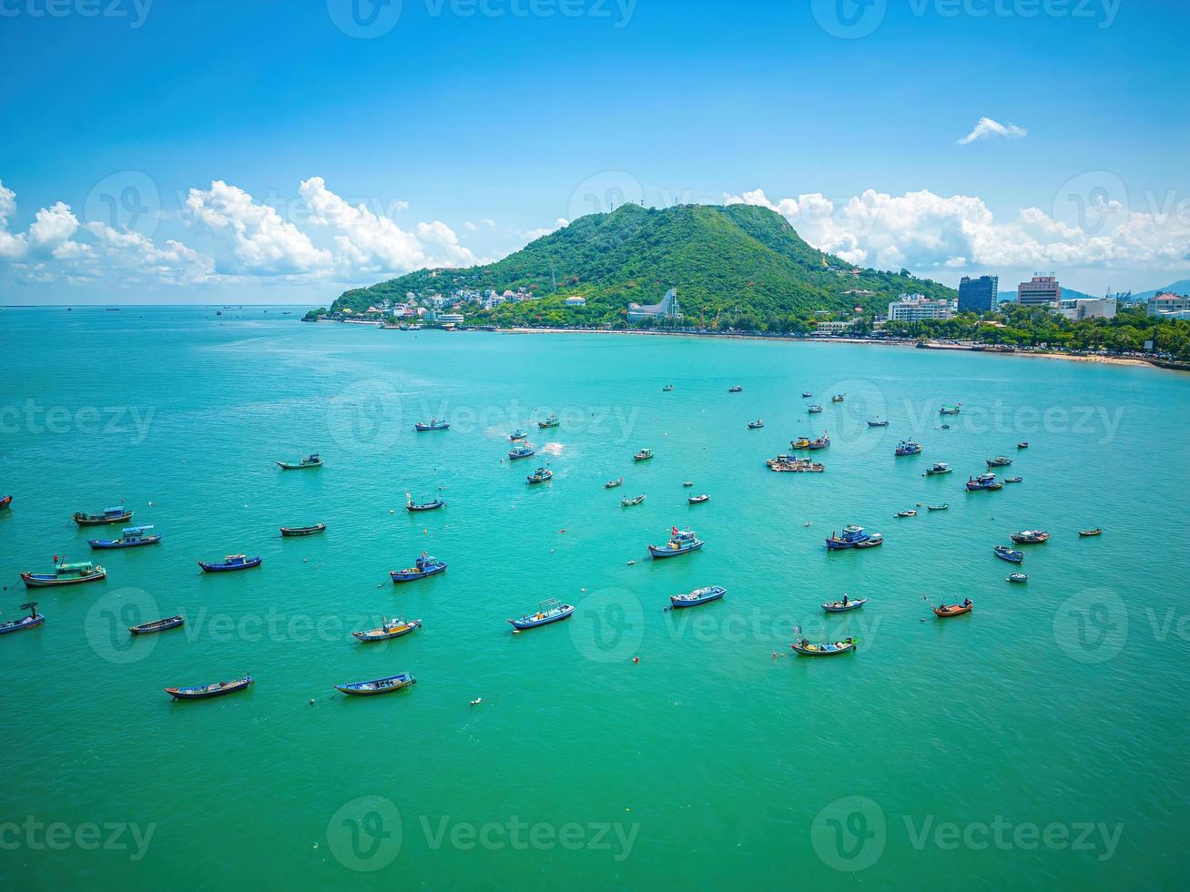 Vung Tau city aerial view with beautiful sunset and so many boats. Panoramic coastal Vung Tau view from above, with waves, coastline, streets, coconut trees and Tao Phung mountain in Vietnam. photo