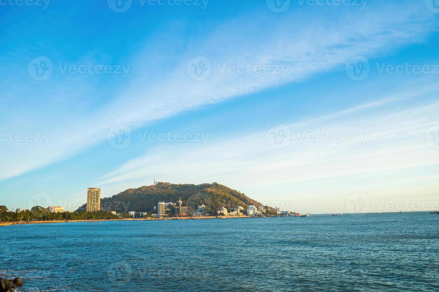 Vung Tau city aerial view with beautiful sunset and so many boats. Panoramic coastal Vung Tau view from above, with waves, coastline, streets, coconut trees and Tao Phung mountain in Vietnam. photo