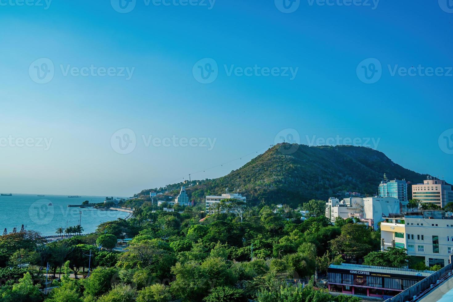 Vung Tau city aerial view with beautiful sunset and so many boats. Panoramic coastal Vung Tau view from above, with waves, coastline, streets, coconut trees and Tao Phung mountain in Vietnam. photo