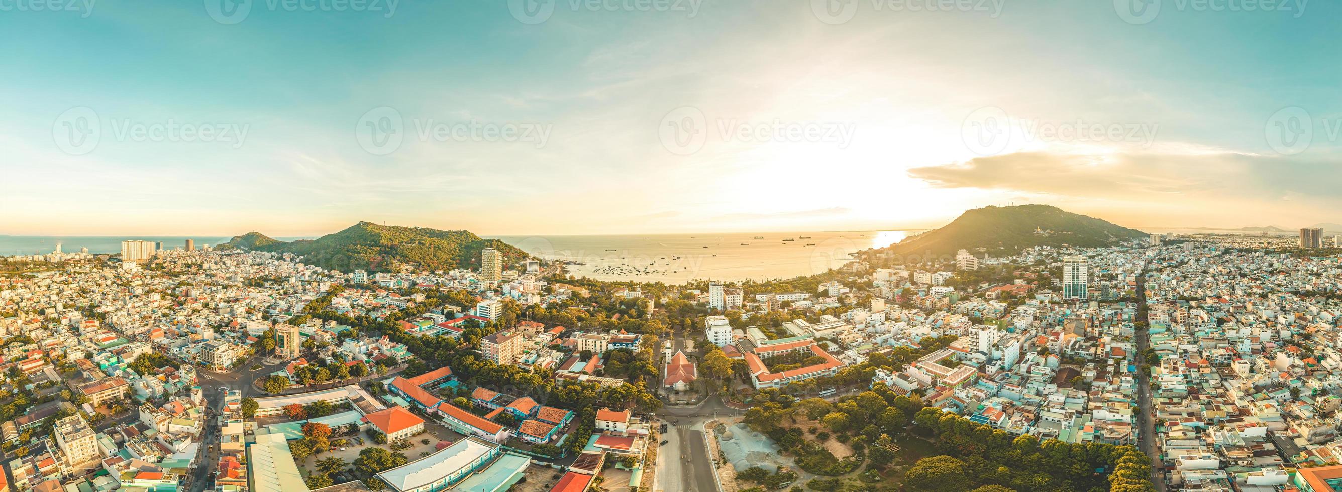 Vung Tau city aerial view with beautiful sunset and so many boats. Panoramic coastal Vung Tau view from above, with waves, coastline, streets, coconut trees and Tao Phung mountain in Vietnam. photo